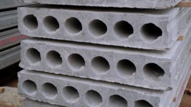 Ortasında delikler olan kocaman beton bloklar. İnşaat malzemeleri dışarıda yığılmış durumda. Kapat..