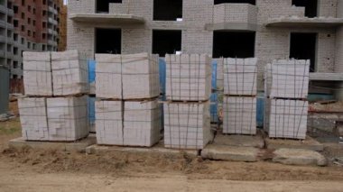 Beyaz tuğlaları ev yapımı için hazırlanmış bir inşaat alanı. Bitmemiş binalar ve arka planda bir vinç.