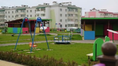 Yeşil çimenleri olan sevimli renkli, rahat oyun alanı. Arkaplanda yeni apartmanlar.