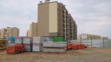 Çok katlı apartmanlardan oluşan yeni bir yerleşim alanı inşaatı. Turna ve inşaat malzemeleri bitmemiş evlerin arka planında.