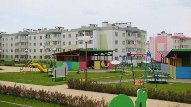 Yeni inşa edilmiş anaokulunun iyi korunmuş toprakları. Yeni evlerin arka planındaki yeşil çimlerde büyük çardaklar ve çaydanlıklar..