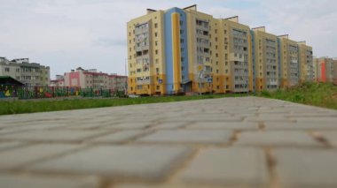 Çok katlı çok katlı güzel apartmanlara giden gri tuğlalardan oluşan bir yol. Arka plandaki anaokulu bölgesi.