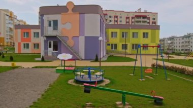 Yeni kreşin hoş görünümlü bölgesi. Yeşil çimlerin üzerinde teeterbolar olan sevimli oyun alanları. Yeni yerleşim alanı arkaplanı.