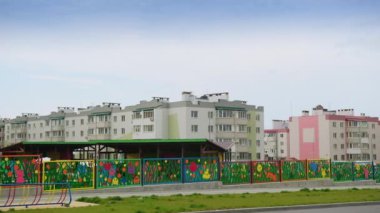 Anaokulu bölgesinin güzel renkli çitleri. Arkaplanda modern apartman blokları.