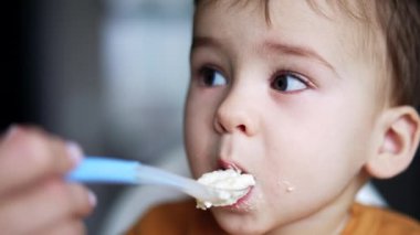 Yiyeceğe bulanmış şirin bebek yüzlü. Yemek yiyen küçük bir çocuğun portresi. Kapatın. Bulanık arkaplan.