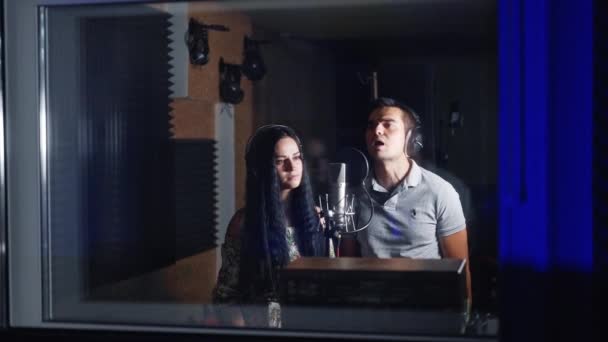 スタジオで歌う歌手の美しいカップル スタジオの暗い部屋で歌と音楽を録音する男女 — ストック動画