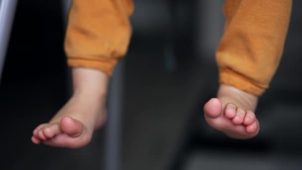 Маленькие Милые Детские Ножки Свисающие Стула Ребенок Оранжевых Штанах Сидит — стоковое видео