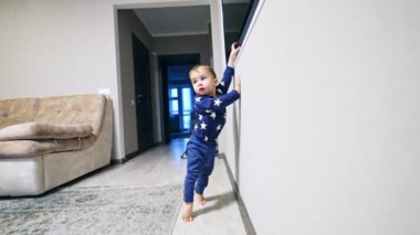 Kafkasyalı çocuk parmaklarının üzerinde durup duvardaki televizyona ulaşmaya çalışıyor. Bebek televizyonu açmaya çalışıyor..