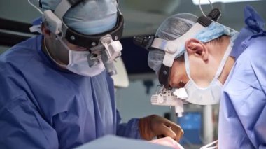 Sinir cerrahisi operasyonunda odaklanmış iki uzman. İşbirlikçi profesyoneller, araçları kullanarak hastanın üzerine eğildi.