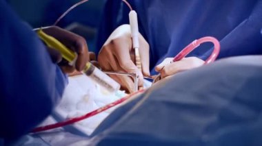 Plastik eldivenli cerrahların elleri ameliyat için gerekli aletleri uyguluyor. Doktora yardım etmek ameliyat bölgesine şırıngadan ilaç koyuyor. Kapat..
