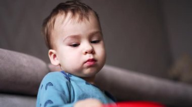 Sevimli beyaz bebek oyuncakla barışçıl bir şekilde oynuyor. Düşük açı. Kapatın. Bulanık arkaplan.