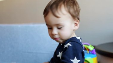 Odada oynayan sevimli beyaz bir erkek bebek. Mutlu gülümseyen çocuk piramit için elini uzatıyor..