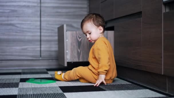 Piękny Biały Chłopczyk Siedzi Podłodze Kuchni Dzieciak Bierze Pokrywę Pojemnika — Wideo stockowe