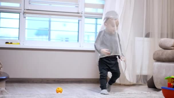 小男孩躲在郁金香后面 然后去找他的玩具 可爱的幼儿坐在地板上玩他的船 — 图库视频影像