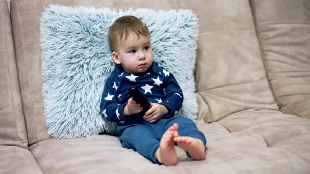 Liebenswerter Kleiner Junge Der Bequem Auf Dem Sofa Sitzt Und — Stockvideo