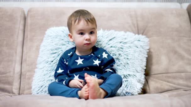Süßes Kleines Kind Das Auf Einem Großen Bequemen Sofa Sitzt — Stockvideo