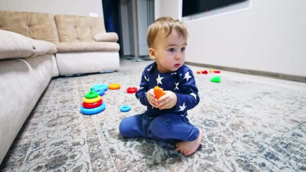 Miły Chłopczyk Siedzi Podłodze Trzymając Zabawkę Rękach Dzieciak Bawi Się — Wideo stockowe