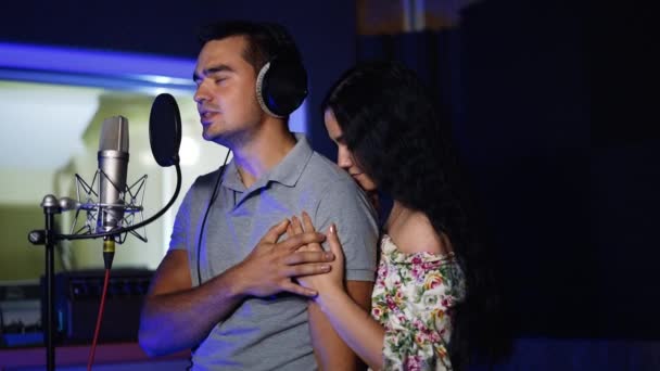 ミュージックレコーディングスタジオのカップル マイクに歌う男と女性は彼が肩に傾いている抱擁 — ストック動画