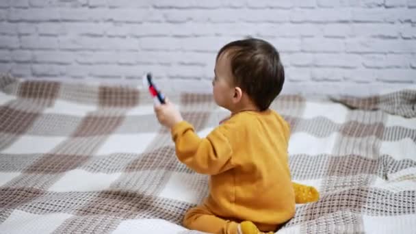 兴奋的孩子跳上了床 一个蹒跚学步的小孩在房间里玩玩具的背景图 — 图库视频影像