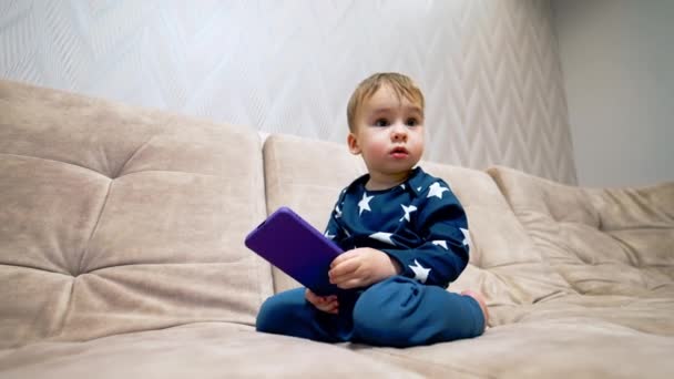 Entzückendes Einjähriges Kleinkind Das Mit Dem Handy Auf Dem Sofa — Stockvideo