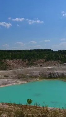 Kaolin taş ocağının güzel manzarası. Derin kil madeni suyla dolu. Gölete yansıyan mavi gökyüzü. Dikey video