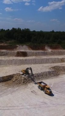 Boş kamyon kazıcıya doğru geri gidiyor. Kamyon, şu anki maden ocağında kaolin kiliyle yükleniyor. Dikey video