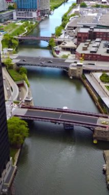 Chicago Nehri üzerindeki köprülerden hızlı arabalar geçiyor. Nehir boyunca giden büyük bir tekne. Havadan bakış açısı. Dikey video