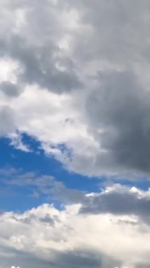 Cennetin güzel bulutları havada hareket ediyor. Parlak güneş ışınlarında kabarık beyaz bulutlar. Düşük açılı zaman dilimi. Dikey video