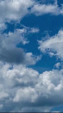 Beyaz yumuşak bulutlar çabucak griye dönüşür. Mavi gökyüzü zaman diliminde yağmur bulutu oluşumu. Aşağıdan bak. Dikey video