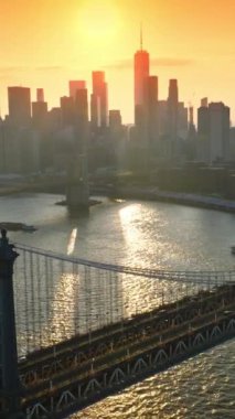 Gün batımında Manhattan Köprüsü 'nde çılgın bir trafik var. Göz kamaştırıcı New York gökdelenleri pembe gökyüzü ve parlak batan güneşin arka planında. Dikey video