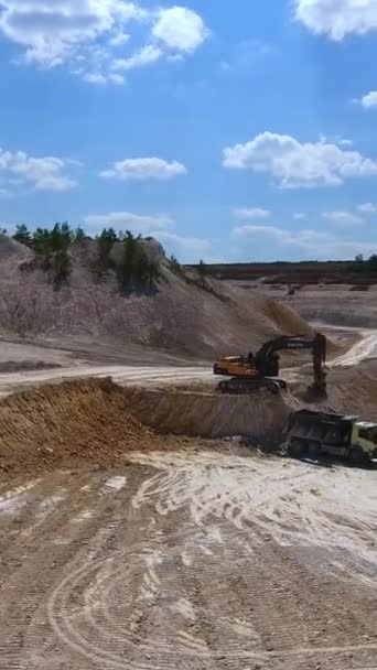 挖掘机在卡车上装载高岭土 今天采石场丘陵地带上空的圆形运动镜头 垂直录像 — 图库视频影像