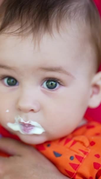 可爱的婴儿坐在妈妈用勺子喂的小圈上 可爱的孩子吃东西 皱着眉头 靠近点垂直录像 — 图库视频影像
