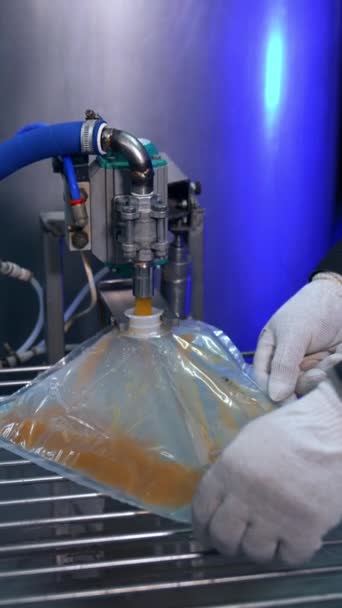 透明的塑料袋通过一个开口装进果汁 工厂工人把袋子磨平 以便更好地灌装果汁 垂直录像 — 图库视频影像