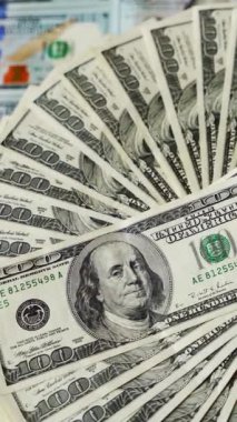 Doların zengin bir geçmişi var. Çember şeklinde dönen 100 dolarlık banknotlar. Masada Amerikan parası var. Para birimi dönüyor. Dikey video