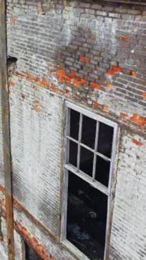 Savaştan sonra penceresi olmayan tuğladan yapılmış bir bina. Duvarında bir sürü delik olan yıkık bir evin yakın görüntüsü. Kamera yukarıdan aşağıya dikey görüntü taşır