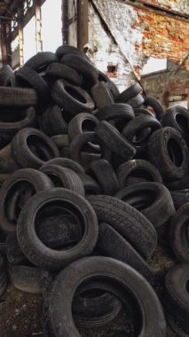 İçindeki terk edilmiş eski fabrikada kullanılmış otomobil lastikleri. Farklı araçlardan devasa siyah atık tekerlekleri. Alt kısmı dikey olarak yukarı hareket ettir