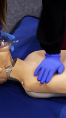Bir manken üzerinde eğitim reanimasyon prosedürü. İnsanlar alıştırma kursunda kuklanın yüzüne solunum cihazı takıyor. Bir hastaya ilk yardım eğitimi. Dikey video