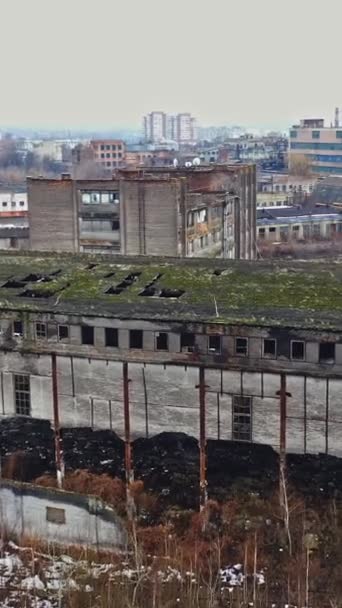 市内の穴の多い屋根でほとんど破壊された建物 破壊された工業ビルと道路上のいくつかの車のトップビュー 航空ビュー 垂直ビデオ — ストック動画