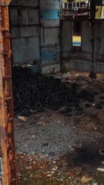 Terk edilmiş fabrikada eski kullanılmış lastikler. Terk edilmiş endüstriyel bir fabrikanın hava görüntüsü Dikey video