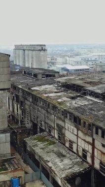 Eski bir fabrika harabesinin ve kırık camların havadan görünüşü. Yıkım için eski endüstriyel bina. Dikey video