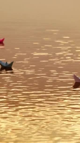 川に浮かぶ色の紙船と いくつかの水が日没時にそれらを少しカバーしています 水面ビデオで4つの折り紙ボートが泳ぐ — ストック動画