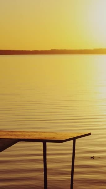 一个男孩的轮廓在湖上的桥上 日落时就能看到 孩子在空桥上慢悠悠地走着 观看着河边美丽的落日 — 图库视频影像