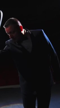 Tiyatroda erkek oyuncu oynuyor. Komik adam beyaz şapkasını takıp sahnede dans etmeye başladı. Sahneden bak. Dikey video