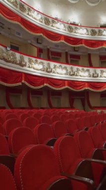 Tiyatroda kırmızı sandalyeler. Kilitleme saatinde seyirci olmadan güzel, boş bir opera salonu. Dünya krizi, finansal kayıplar, salgının sonuçları. Dikey video