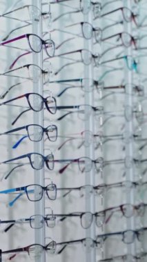 Güzel kız yeni gözlük seçiyor. Optik mağazasında şık gözlükler deneyen gülümseyen sarışın kadın. Göz giyimi konsepti. Dikey video