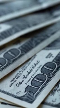 Yüz dolarlık banknotlar dönüyor. Kağıt paranın rotasyonu. Amerikan yüz dolarlık banknotlarla dolu bir geçmiş. Yakın plan. Dikey video