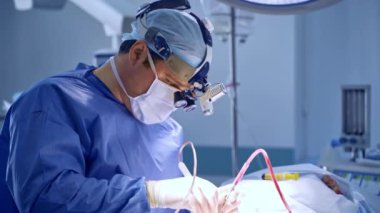 Meşgul erkek beyin cerrahı ameliyat sırasında elektrikli alet uyguluyor. Doktor enstrümanı asistana verir ve yenisini bekler..