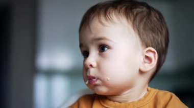 Ağzında yemek olan güzel beyaz bir erkek bebek. Annem mandıralı kaşığı oğluna veriyor. Düşük açı görünümü.