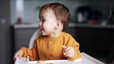 Yemekler sırasında eğlenen sevimli bir çocuk. Çocuk yemek masasında oturur ve anne kaşığa yemek koyar..