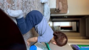 Tatlı küçük bebek oyuncaklarla huzur içinde oynuyor. Oturma odasında oyun oynayan sevimli çocuk. Dikey video.